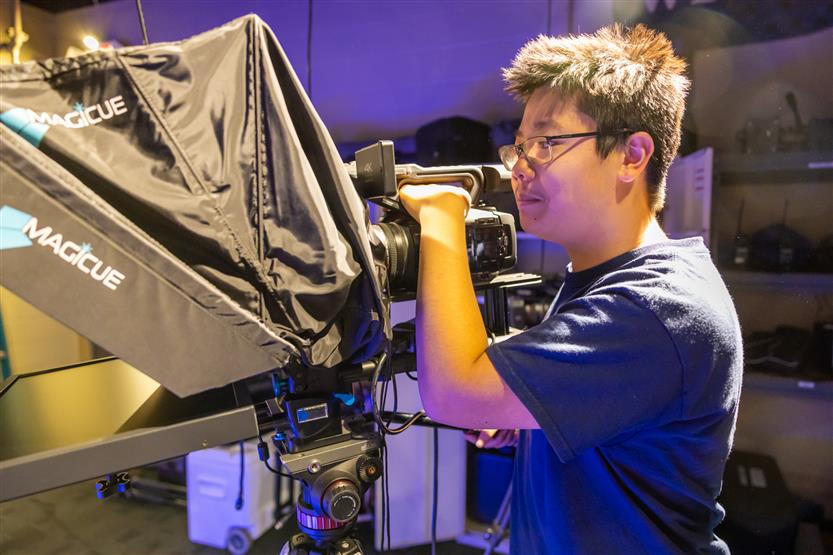 A student stands at a camera